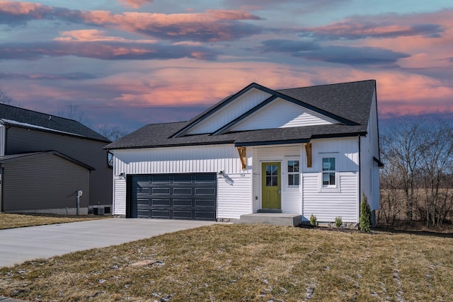 view of front of house with cooling unit, a garage, and a yard