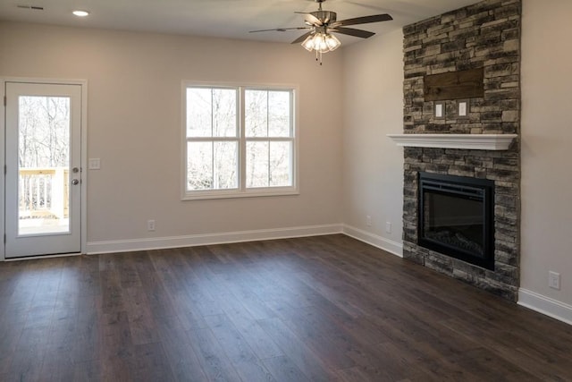 unfurnished living room with a stone fireplace, dark hardwood / wood-style floors, and ceiling fan