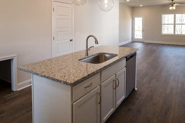 kitchen featuring dark hardwood / wood-style floors, dishwasher, sink, a kitchen island with sink, and light stone countertops