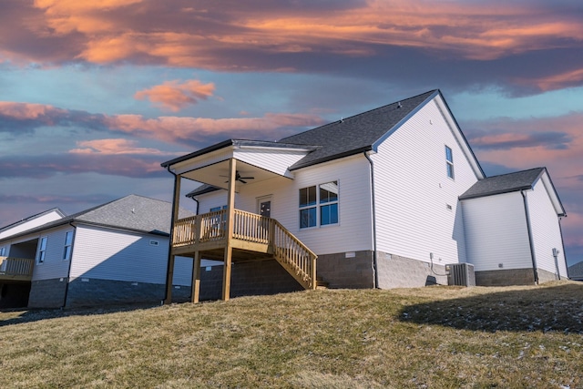 back house at dusk with cooling unit, a yard, ceiling fan, and a deck