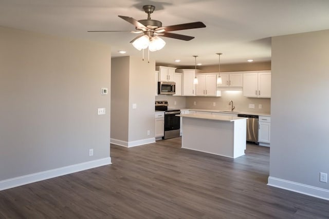 kitchen featuring pendant lighting, white cabinetry, sink, a center island, and stainless steel appliances