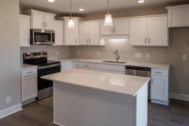 kitchen with a kitchen island, white cabinetry, sink, hanging light fixtures, and stainless steel appliances