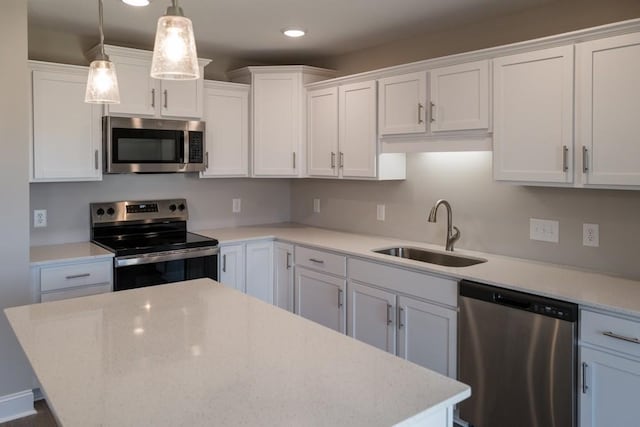 kitchen with pendant lighting, appliances with stainless steel finishes, sink, and white cabinets