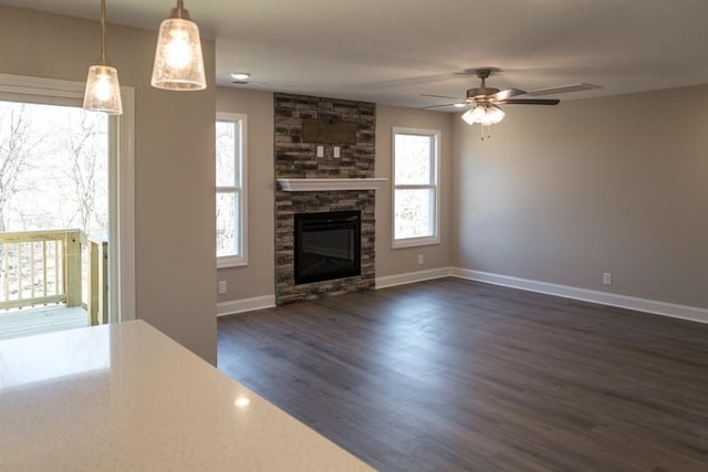 unfurnished living room featuring ceiling fan, dark wood-type flooring, and a fireplace