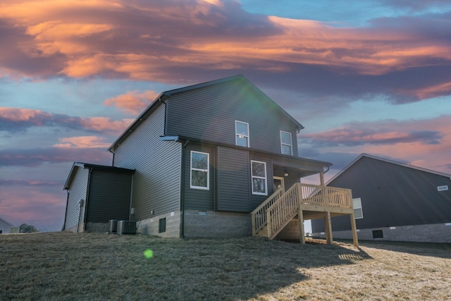 back house at dusk with a wooden deck and a lawn