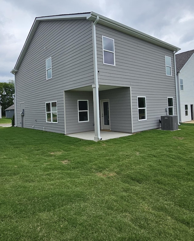 back of property with a lawn, central AC, and a patio area