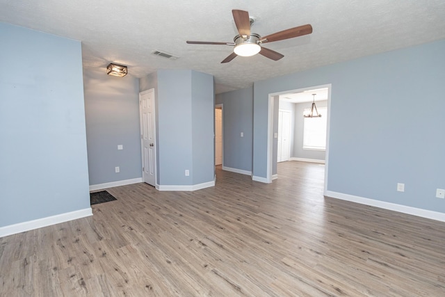 spare room with ceiling fan with notable chandelier, hardwood / wood-style floors, and a textured ceiling