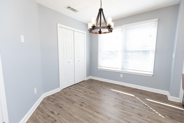 unfurnished dining area with dark wood-type flooring and an inviting chandelier