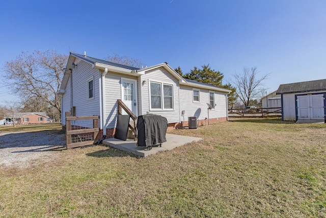 back of property with a storage shed, a patio area, a lawn, and central air condition unit