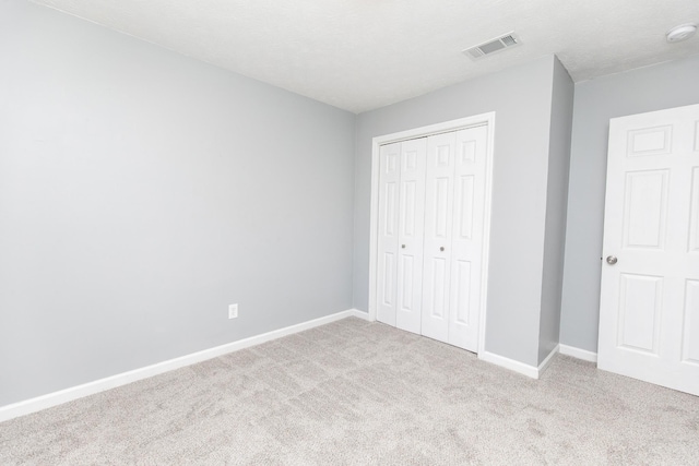 unfurnished bedroom with light colored carpet, a closet, and a textured ceiling