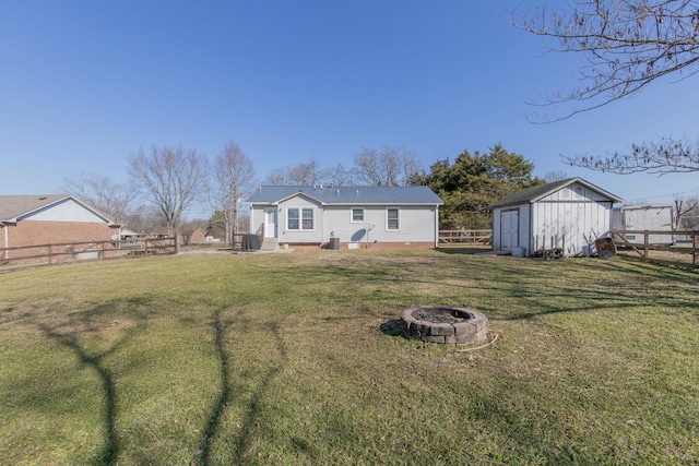 rear view of property with a storage shed, a yard, and an outdoor fire pit