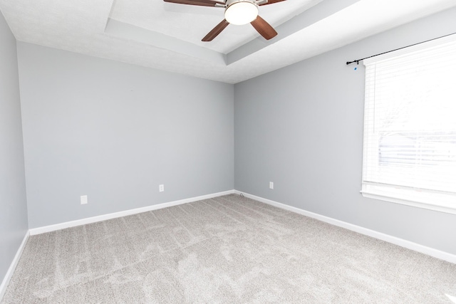 spare room with ceiling fan, a healthy amount of sunlight, a tray ceiling, and carpet floors