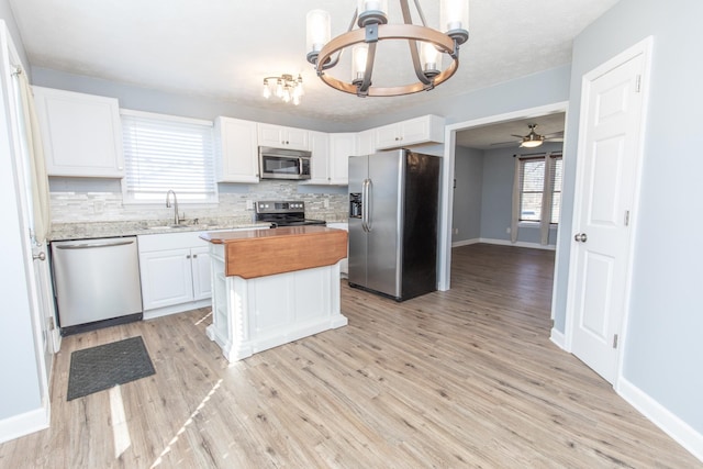 kitchen featuring white cabinetry, stainless steel appliances, sink, and a kitchen island