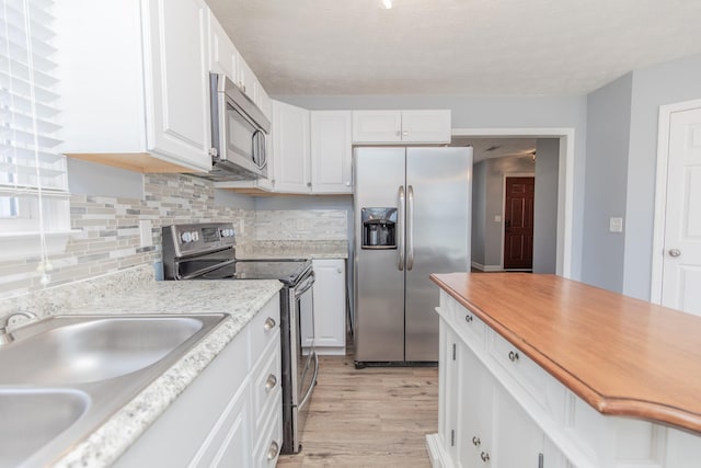 kitchen featuring stainless steel appliances, sink, light hardwood / wood-style flooring, and white cabinets