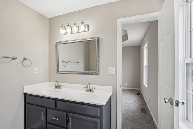 full bath featuring double vanity, a sink, visible vents, and baseboards