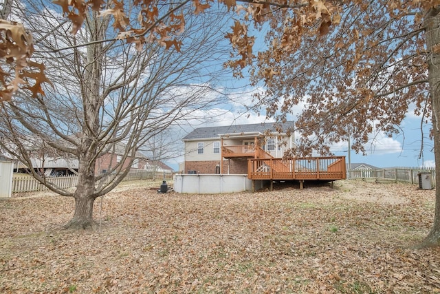 back of house featuring a deck, brick siding, fence, and a fenced in pool