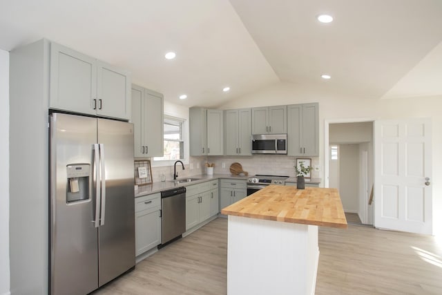 kitchen with wood counters, lofted ceiling, sink, a center island, and stainless steel appliances