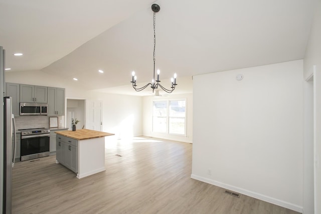 kitchen featuring gray cabinets, a kitchen island, appliances with stainless steel finishes, pendant lighting, and butcher block counters