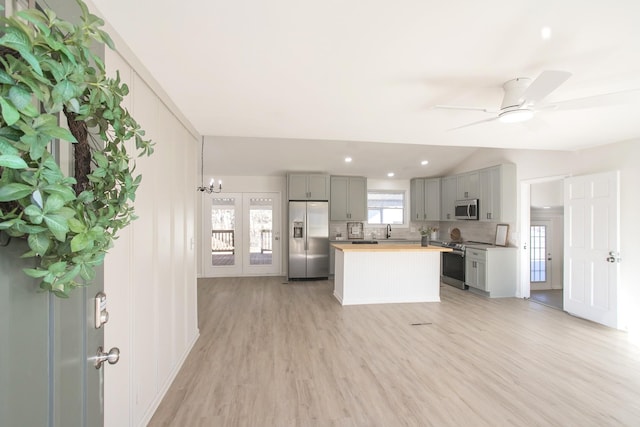 kitchen featuring wood counters, light wood-type flooring, gray cabinets, stainless steel appliances, and backsplash