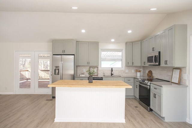 kitchen with wood counters, sink, appliances with stainless steel finishes, gray cabinets, and a kitchen island