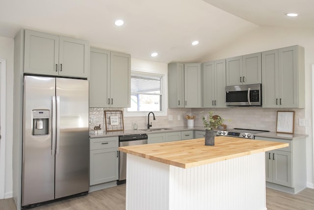 kitchen featuring lofted ceiling, sink, wooden counters, a kitchen island, and stainless steel appliances