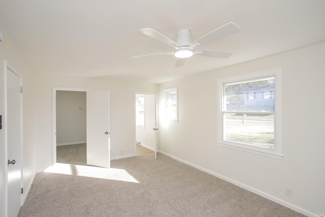 unfurnished bedroom with ceiling fan, a spacious closet, and light carpet