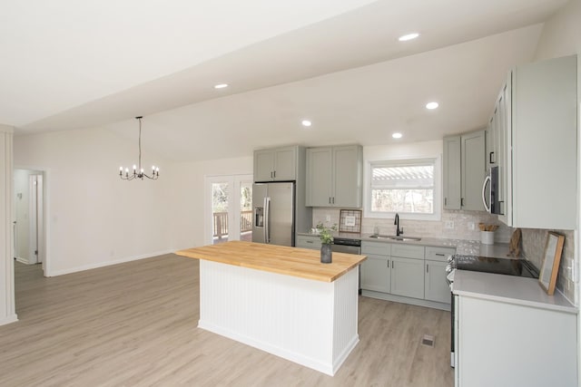 kitchen with sink, butcher block counters, stainless steel appliances, a center island, and a wealth of natural light