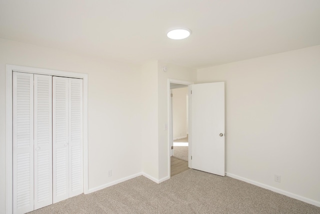 unfurnished bedroom with light colored carpet and a closet