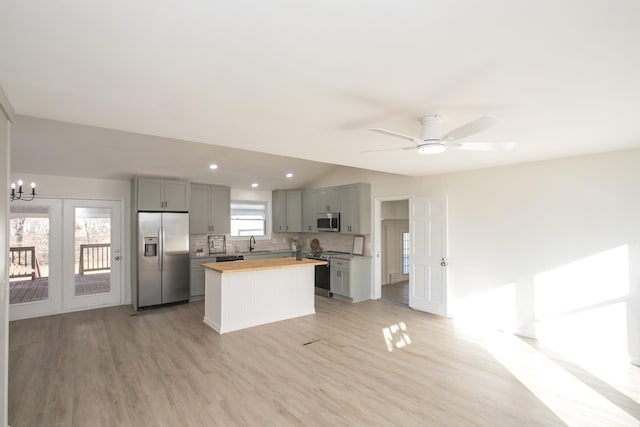 kitchen with gray cabinets, light hardwood / wood-style flooring, butcher block counters, stainless steel appliances, and tasteful backsplash