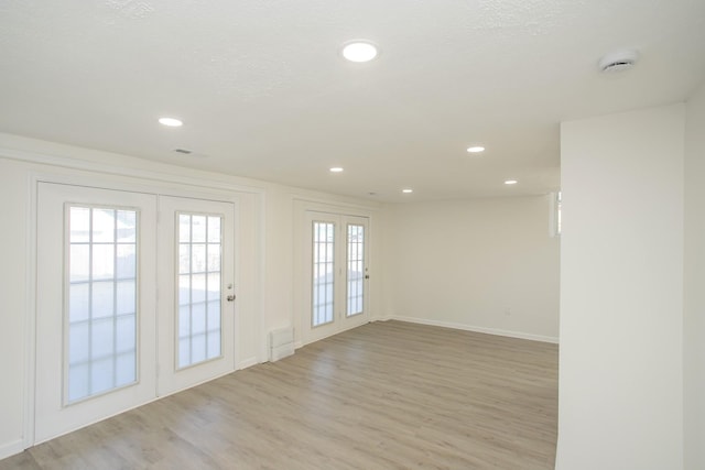 unfurnished room with a textured ceiling, light hardwood / wood-style flooring, french doors, and a healthy amount of sunlight