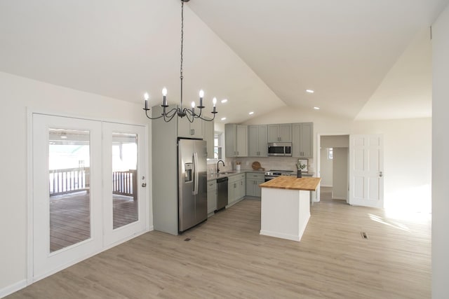 kitchen with butcher block countertops, gray cabinets, appliances with stainless steel finishes, a center island, and decorative light fixtures