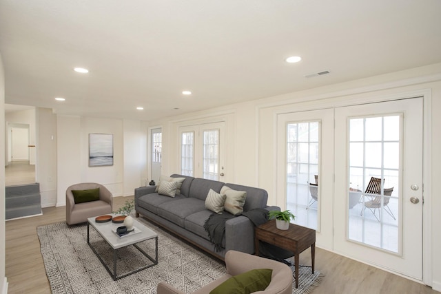 living room with light hardwood / wood-style flooring, french doors, and plenty of natural light