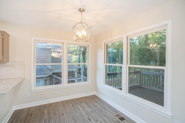 unfurnished dining area featuring wood-type flooring and a notable chandelier