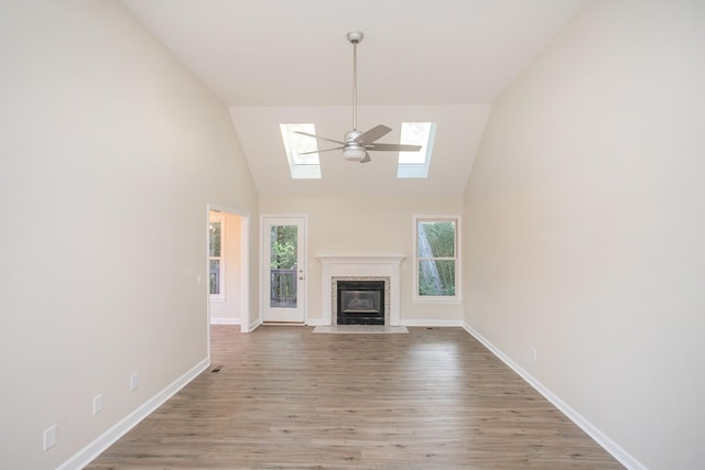 unfurnished living room with light hardwood / wood-style flooring, a skylight, and high vaulted ceiling