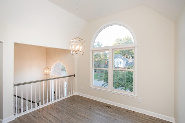 spare room featuring an inviting chandelier, dark hardwood / wood-style flooring, and a wealth of natural light