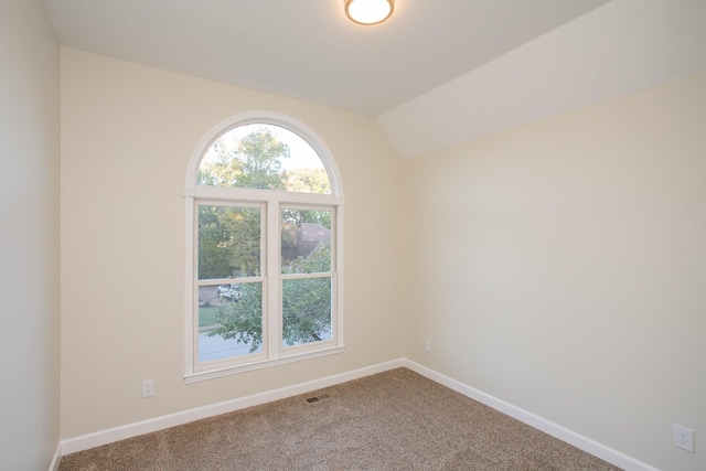 carpeted spare room with lofted ceiling