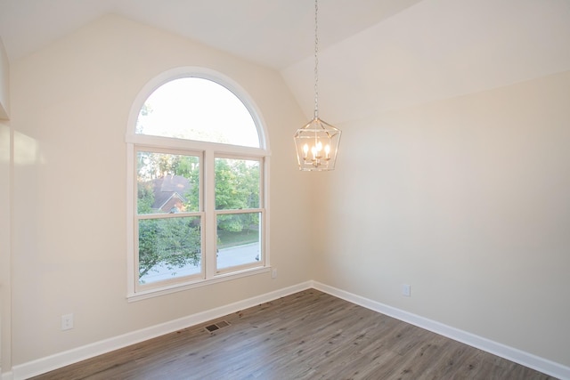 empty room featuring lofted ceiling, plenty of natural light, an inviting chandelier, and dark hardwood / wood-style flooring