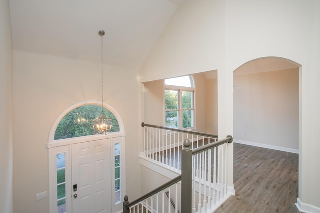 entryway featuring an inviting chandelier, wood-type flooring, and high vaulted ceiling