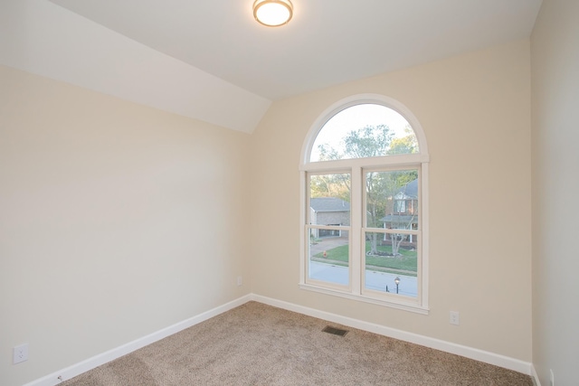 unfurnished room featuring light carpet and vaulted ceiling