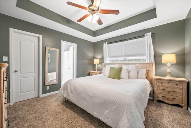 carpeted bedroom with ceiling fan and a tray ceiling