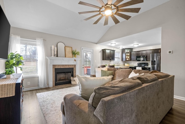 living room with vaulted ceiling, a fireplace, sink, dark hardwood / wood-style flooring, and ceiling fan