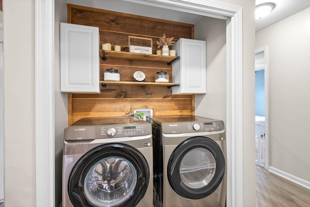 laundry area featuring cabinets, light hardwood / wood-style floors, and washer and dryer