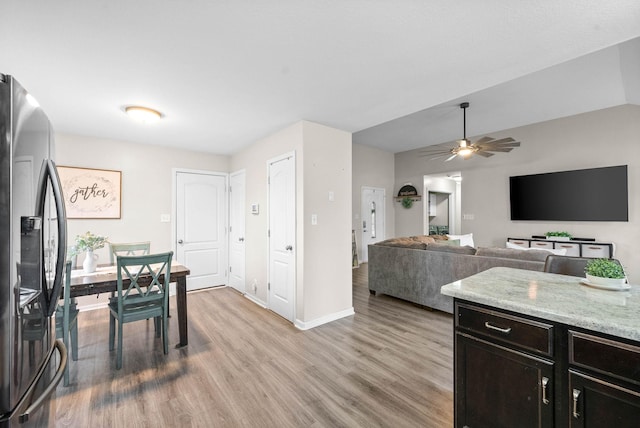 kitchen featuring stainless steel refrigerator with ice dispenser, light stone counters, ceiling fan, and light hardwood / wood-style flooring