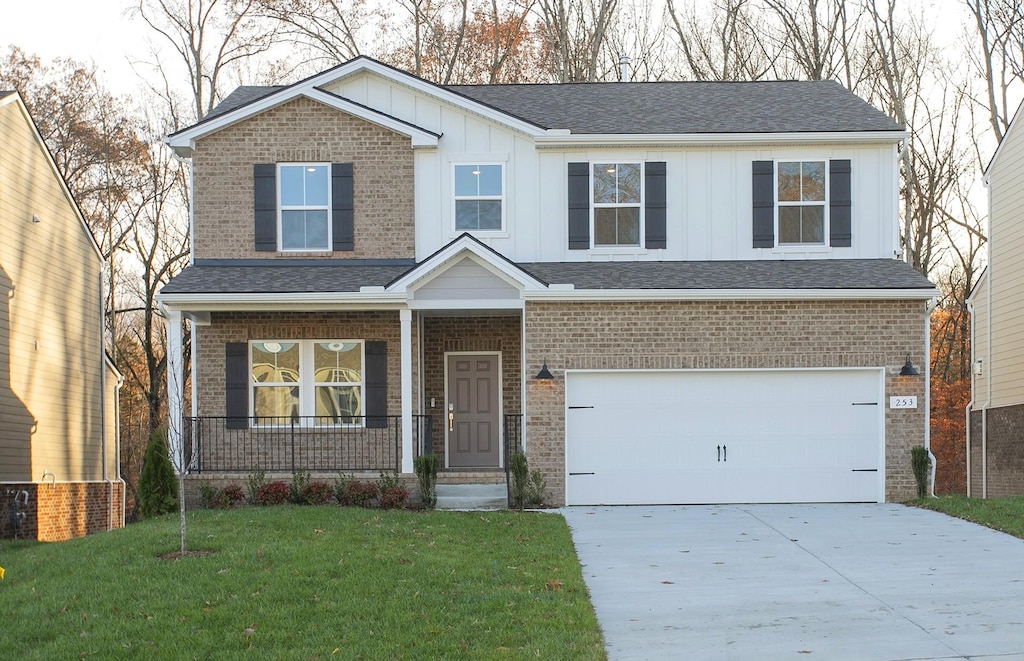 view of front of home featuring a garage, a front yard, and covered porch