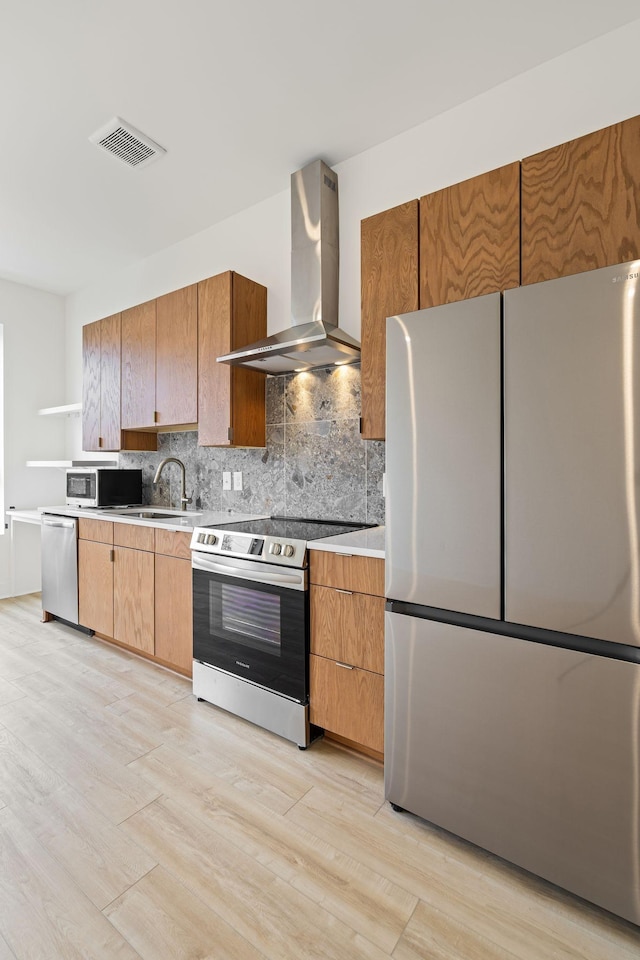 kitchen featuring sink, light hardwood / wood-style flooring, stainless steel appliances, tasteful backsplash, and exhaust hood