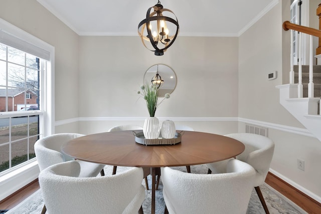 dining space with crown molding, wood-type flooring, and a notable chandelier