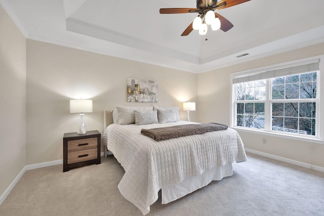 carpeted bedroom featuring ceiling fan, ornamental molding, and a tray ceiling