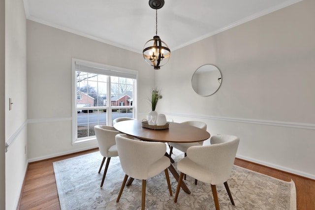 dining area with a notable chandelier, ornamental molding, and light wood-type flooring