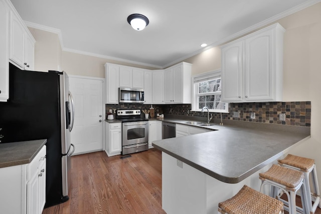 kitchen featuring white cabinetry, stainless steel appliances, kitchen peninsula, and sink