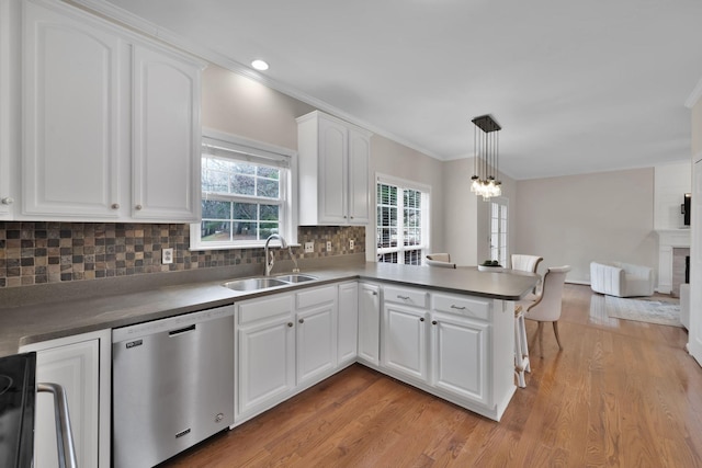 kitchen with sink, white cabinets, decorative light fixtures, stainless steel dishwasher, and kitchen peninsula